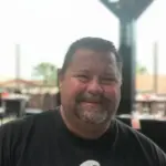 Tom Thomson smiling at an outdoor dining area. A satisfied customer of McMahan Rolloffs in Greenfield, Indiana, sharing his positive experience with dumpster rental and waste removal services.